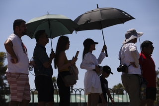 People use an umbrella to block the sun while waiting to take a picture at the “Welcome to Las Vegas” sign Monday, July 8, 2024, in Las Vegas. WADE VANDERVORT
