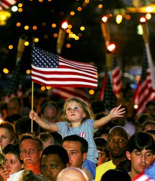 Alana Milawski, 3, waves an American flag as she sits on her father Craig Milawski's shoulders during a candlelight vigil at the Thomas & Mack Center Wednesday, Sept. 12, 2001, held to honor those killed in the Sept. 11 terrorist attacks. 