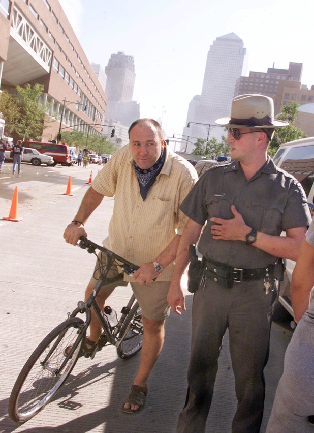 Actor James Gandolfini, left, is astride his bicycle as he talks with a police officer, Wednesday Sept. 12, 2001, near the scene of the terrorist attack on the twin towers of World Trade Center.  