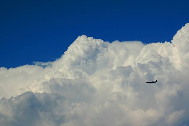 A plane landing at McCarran International Airport from the east, passes a large cloud during the monsoon season.
