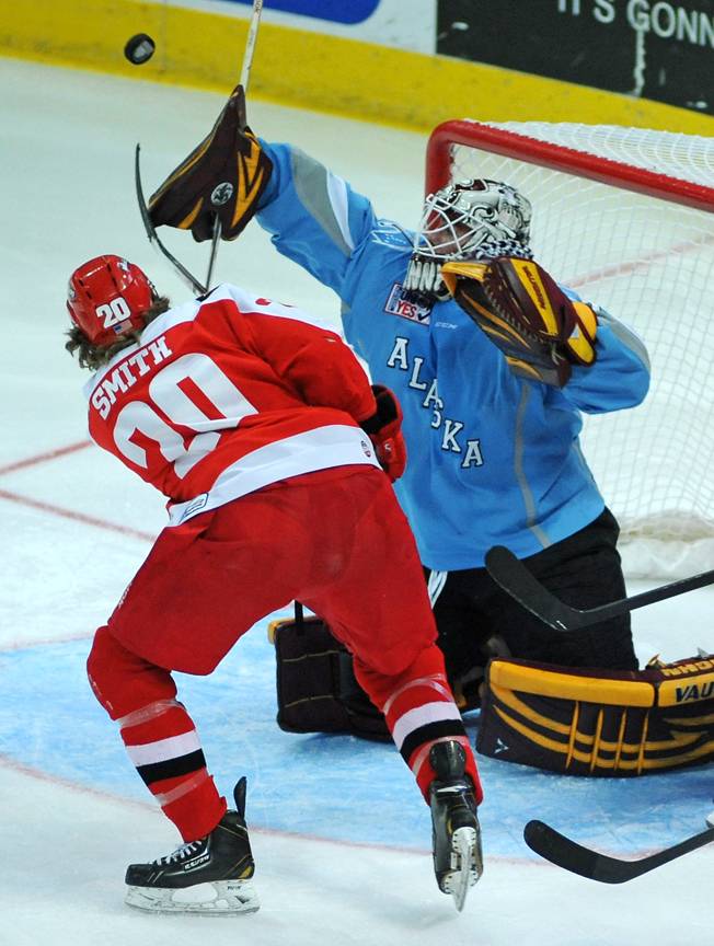 Alaska Aces goaltender Aaron Crandal deflects a shot with his blocker as Las Vegas Wranglers forward Robbie Smith swings his stick at the fluttering puck during the second period of play on Saturday night.