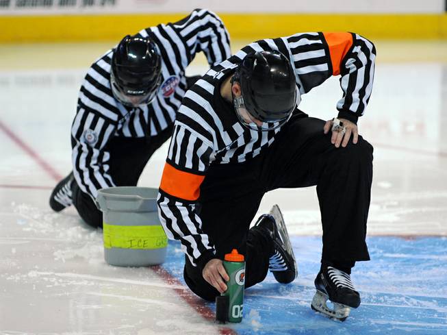 ECHL referee Ryan Murphy and linesman Wally Lacroix help make repairs to the ice surface near where the goal pegs are inserted before the start of the third period between the Wranglers and the Colorado Eagles on Wednesday night at the Orleans Arena.