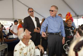 Senate Majority Leader Harry Reid, center, smiles as he chats with retired union carpenter Damon Bingle, left, who recently turned 90 years old, during an early Labor Day celebration for union members and their families in downtown Las Vegas on Thursday.