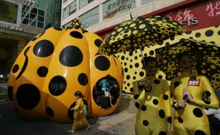 Models pose in front of the giant pumpkin which is created by Japanese artist Yayoi Kusama during the opening ceremony of Kusama's art exhibition in Hong Kong Tuesday, Oct 9, 2007. The 5 meters wide, 5 meters deep and 4.2 meters high pumpkin which decorating by black dot can allow people to enter. 