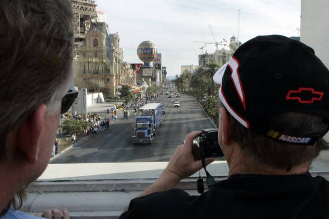 Tom Hale, left, and Ray Gadd of Owosso, Mich. take a photo as the last of the NASCAR car haulers, the 18-wheelers that transport the race cars and teams to each track, parades northbound on Las Vegas Boulevard on Thursday. 