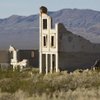 The remains of the Cook Bank building in Rhyolite are silhouetted against mountains. The ghost town was founded by miners and pioneers in the early 20th century after gold was discovered nearby.