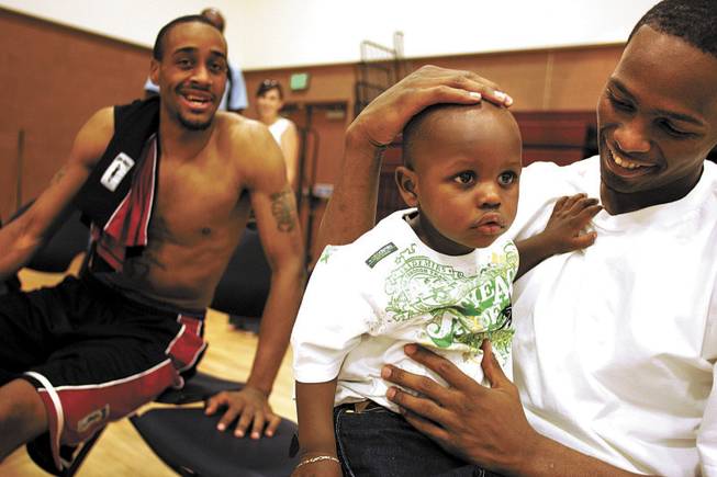 Stars player Eddie Shelby sits with his year-old son, Elijah, after the Stars' win against Elgin. Shelby combined with Demario Butler for 60 points in the victory.