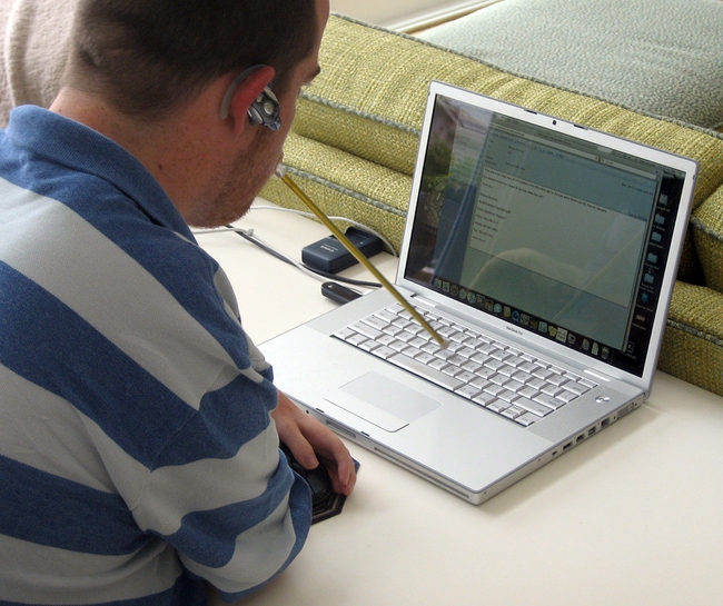 Quinn, a UNLV sophomore, types his column with a pointer held in his mouth.