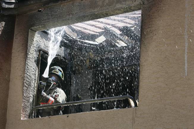 Firefighters work to extinguish a fire today at the Mesa Club Apartments in Henderson. No one was at home in either unit that was damaged. 