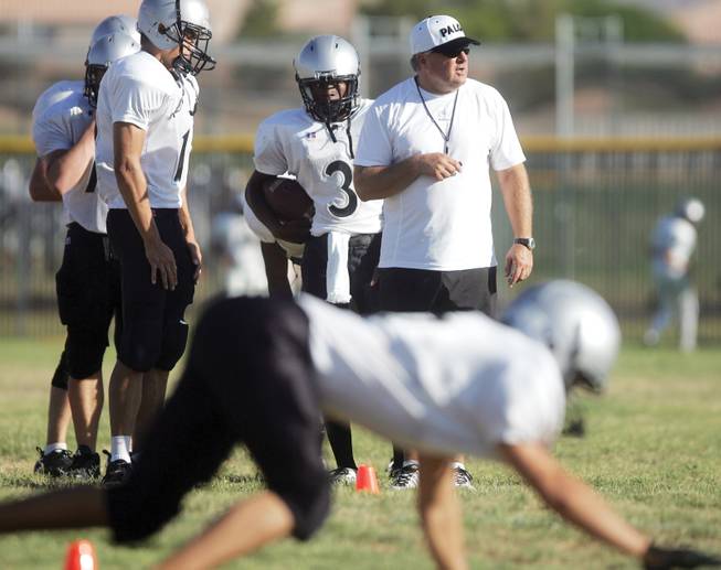 Coach Darwin Rost watches as his players run through a drill during the first day of full contact football practice at Palo Verde High School on Monday.