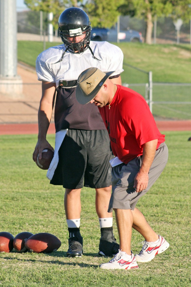 Las Vegas High quarterback's coach Zach Ordish gives senior QB Emir Lopez a few pointers during practice Monday night at LVHS.