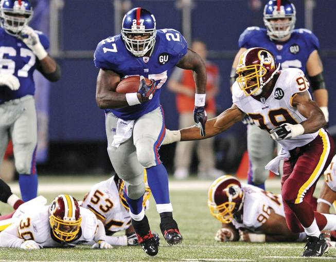 New York Giants running back Brandon Jacobs is in the midst of a 16-yard run as the Washington Redskins' Andre Carter, right, closes in during New York's 16-7 win Thursday at Giants Stadium in East Rutherford, N.J. In Nevada casinos football is king -- last year college and NFL bets totaled a record $1.17 billion, up from $1.13 billion in 2006.
