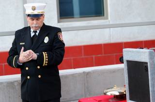 Timothy R. Szymanski, public information officer for Las Vegas Fire & Rescue,  looks at his watch, waiting for 6:54 to ring the bell in tribute at Las Vegas Fire Station No. 5 for the 343 firefighters who lost their lives on Sept. 11, 2001.