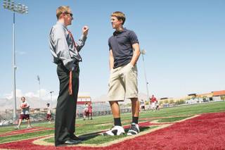 With the aid of a cochlear implant, cornerback Adam Finlayson, right, who is deaf, talks football strategy with coach Jake Kothe between classes at Faith Lutheran High School.
