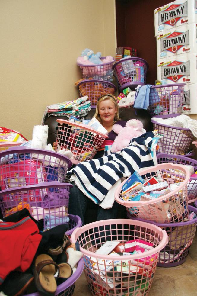 Mattie Wendel, 13, sits in a pile of goods donated for Olive Crest Foster Care and the Shade Tree Shelter.