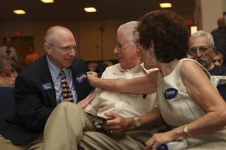 While greeting guests Thursday at the Porter campaign rally, District 20 Assemblyman Joe Hardy receives a sticker from Rep. Jon Porter supporters Charlie and Ada Harris, right, before former Massachusetts Gov. Mitt Romney takes the stage at Boulder City High School.