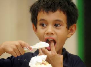 Unable to restrain himself, Lucca Mamone, age 5, sneaks a taste of icing as he spreads it on a cupcake during a Little Pastry Chef after-school program at Frank Lamping Elementary School Oct. 2.  