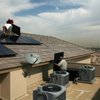Bombard Electric electricians Frank Cudia and Tina Long, on the roof, and Debbie Long install solar panels on a home in Las Vegas.