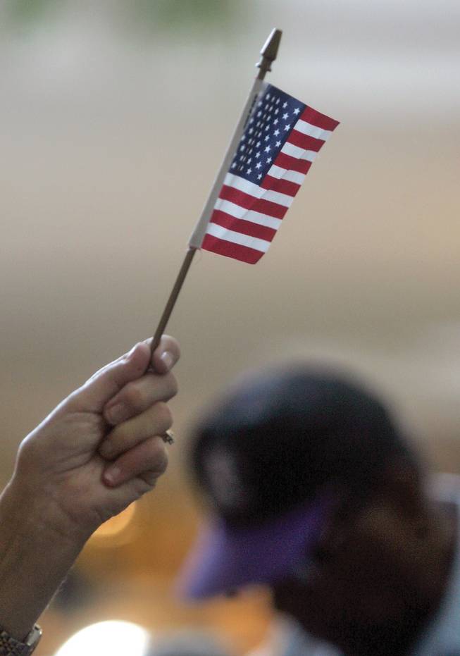 Rosemarie Daniel, a worker with the Clark County Election Department, waves an American flag to direct early voters at Galleria Mall on Monday.