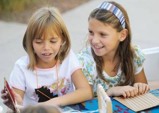 Anabelle Farnham, 8, right, and Sofia Silvestri, 9, both of Summerlin, enjoy the time working on weaving in the Kids Art Park section of the Trails Village Center Art Walk on Sunday.