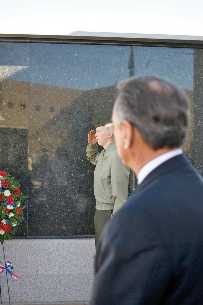 In a solemn ceremony, Marine Corps cadet Bryant Jones, center, salutes the wreath honoring all U.S. veterans at the City of Henderson's Veterans Memorial Wall on Saturday.