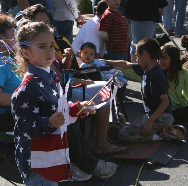 A little girl looks on as veterans wave and salute the crowd at the annual Veterans Day parade Tuesday.