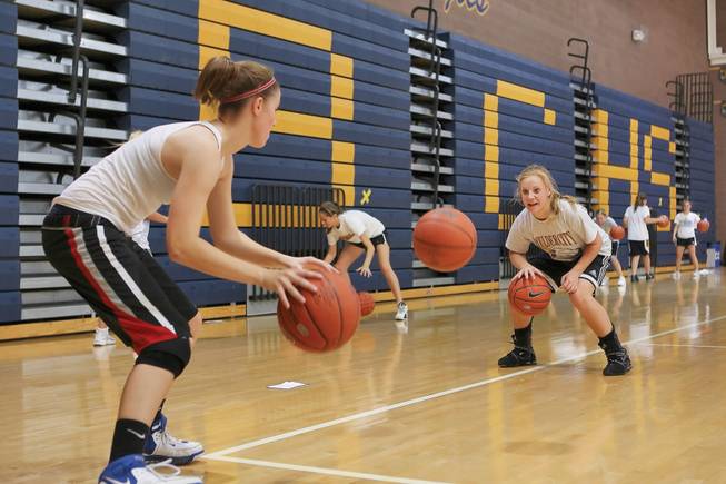 Working as a team, junior Bridget Ward and sophomore Bree Moraing, right, execute the "two-man, three-ball" drill during team practice at Boulder City High on Sunday.