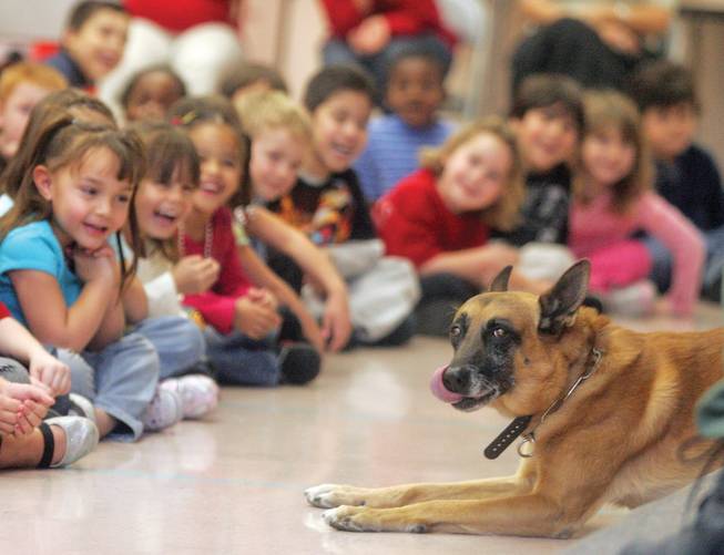 Students laugh as police dog Rico does a trick during his visit to Kahre Elementary School with Metro Police officer Duwayne Layton.