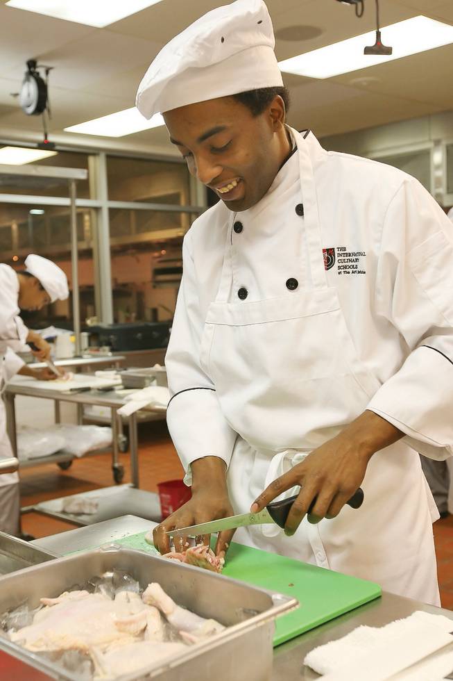Student chef Alonzo Adams chops up a chicken while learning how to creatively bake chicken during a Meat Week class at The International Culinary School at the Art Institute of Las Vegas. Adams was recently featured on the Food Network reality TV show "The Chef Jeff Project."