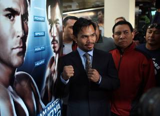 Manny Pacquiao poses by a sign promoting his welterweight fight with Oscar De La Hoya as he makes his official 