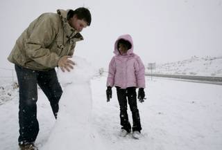 Alexis Winston, 5, and Ryan Cuevas build a snowman on the side of the road near Red Rock Canyon on Monday. 