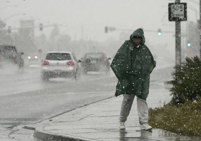 A pedestrian walks through a snowstorm near Rainbow and Charleston ...
