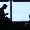 Pullin Sheth, left, of San Jose, Calif., listens to an iPod and plays games on his phone during a flight delay this month at McCarran International Airport. As of November, the overall capacity at the airport serving Las Vegas is down 15 percent from a year ago.