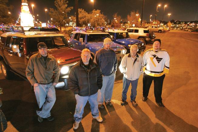 From left, Ty Schubarth, Julian Tosh, Damien Huggard, Bruce Morgan and Dan Johnson, members of the 702 FJ Crew car club, pose for a photo next to their decorated vehicles before heading out with other members of the club to view holiday displays around town on Friday.