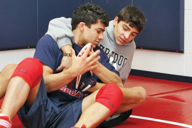 Rudy and Mike Reveles, front, work on wrestling moves together during a practice at Liberty High School.