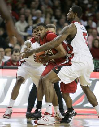 UNLV's Oscar Bellfield looks for help as he is trapped between Louisville defenders Edgar Sosa, left, and Earl Clark during the first half.