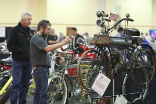 While Craig Murray watches, Terry Cutler takes a photograph of a rare 1907 Yale-California motorcycle Friday during the Las Vegas Antique Motorcycle Auction at the South Point Events Center.  This motorcycle with original paint was originally purchased by a mailman and used to deliver mail.
