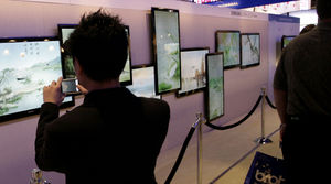 A show attendee takes a picture of a TV display Sunday at CES in Las Vegas Convention Center.
