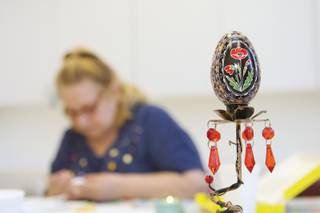A Ukrainian Easter egg deorated with a poppy, the national flower of Ukraine, is displayed as an example while Dee Poya, 65, creates an egg during the Pysanky craft class held at the Henderson Senior Center Tuesday.