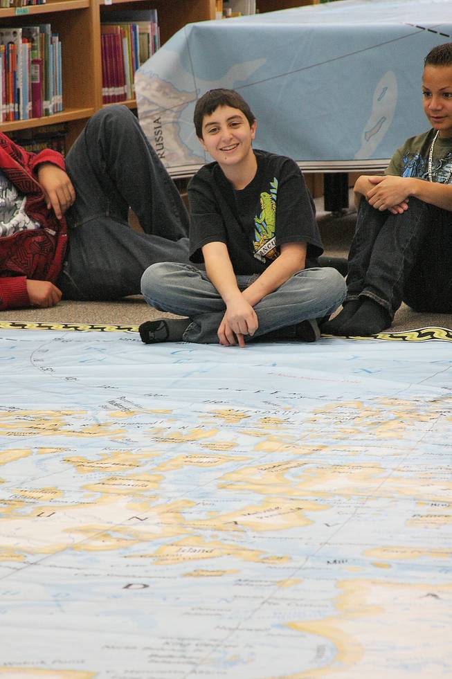 Med Kutob, 13, sits barefoot at the edge of an enlarged map of North America, which his class used to study before mid-terms.