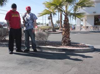Friends Guillermo, left, and Saul, who did not want to give their last names, stand over the spot where their friend, a 21-year-old man known as 