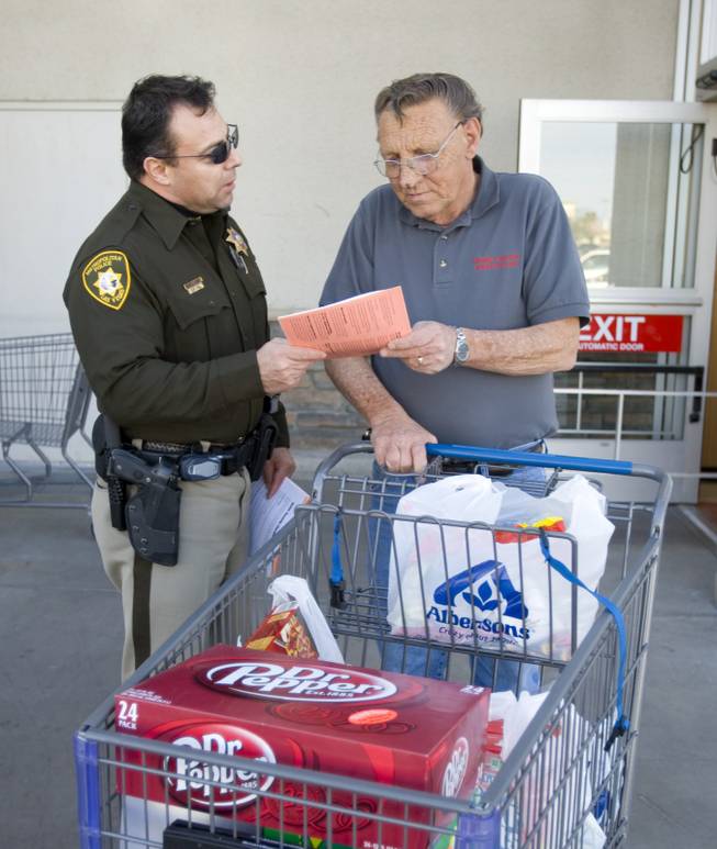 Officer Art Chavez hands Dave Miller information on home burglary prevention Thursday at the Albertsons on Silverado Ranch Boulevard and Maryland Parkway