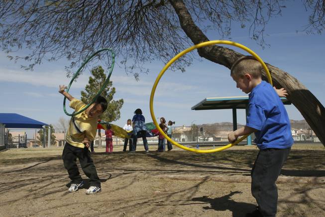 Kindergartners Kyle Lobaugh and Stryder Brown, right, twirl hula hoops on their arms during kindergarten field day Friday at John Dooley Elementary School.