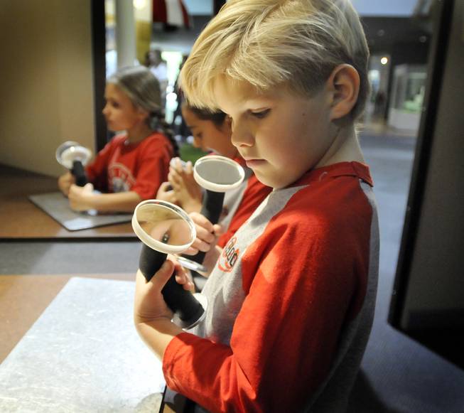 First-grader Anthon Atkins, admires himself with mirrors in a solar energy display at new Green Village at the Lied Discovery Children's Museum on Tuesday. The new 3,500 square-foot mini-city has an environmentally friendly focus that includes exhibits with lessons in everyday living and environmental sustainability.