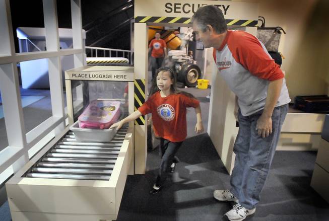 First-grader Kalai Furado, from the Green Valley Christian School, runs through the airport security checkpoint exhibit to get her bag as Dan Woolston watches on. The two, along with about 60 other students from the school, visited the new Green Village display at the Lied Discovery Children's Museum on Tuesday. The new 3,500 square-foot mini-city has an environmentally friendly focus that includes exhibits with lessons in everyday living and environmental sustainability.
