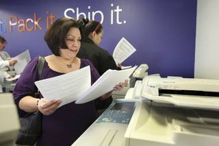 Lisa Her looks at her freshly printed resumes Tuesday at the FedEx Office at 671 Mall Ring Circle in Henderson. Her lost her job in October. FedEx Office locations nationwide offered job seekers free printing of 25 resumes on premium papers Tuesday during 