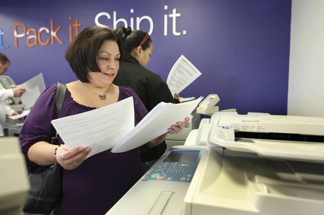 Lisa Her looks at her freshly printed resumes Tuesday at the FedEx Office at 671 Mall Ring Circle in Henderson. Her lost her job in October. FedEx Office locations nationwide offered job seekers free printing of 25 resumes on premium papers Tuesday during "FedEx Office's Free Resume Printing Day."