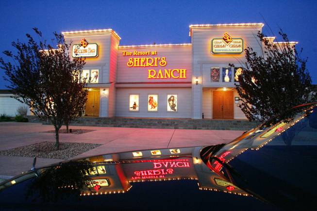 The lights of Sheri’s Ranch in Pahrump are reflected in the hood of a limousine parked in front.