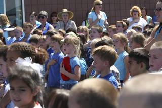Six-year-old Hannah Robinson, center, places her red baseball cap on her heart while saying the Pledge of Allegiance Wednesday during the rededication ceremony of Gordon McCaw Elementary School.