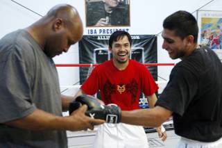 Junior welterweight boxer Manny Pacquiao, center, of Philippines laughs with lightweight boxer Amir Khan, right, of England during a workout in a gym in Las Vegas, Nevada April 30, 2009. Assistant trainer Michael Moorer is at left. Pacquiao will take on Ricky Hatton of England in a 12-round bout at the MGM Grand Garden Arena Saturday.